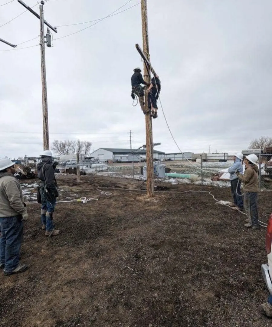 Two people working on a power pole